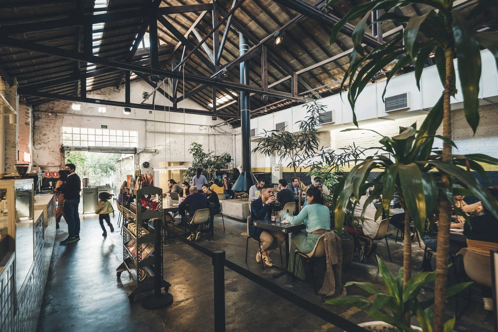 The converted warehouse dining room with communal tables and plants at Futuro Refeitório